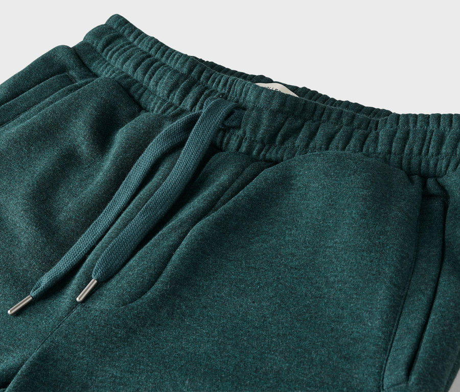 Detailaufnahme einer grünen Jogginghose mit elastischem Bund und Kordelzug.
