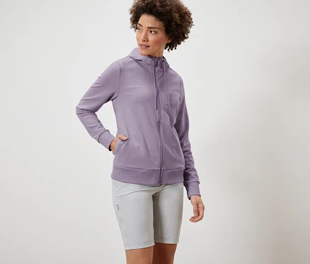 Frau trägt eine lila Sweatjacke und graue Shorts.