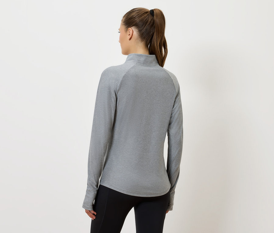 Frau mit dem Rücken zur Kamera trägt ein graues langärmliges Oberteil und eine schwarze Hose.