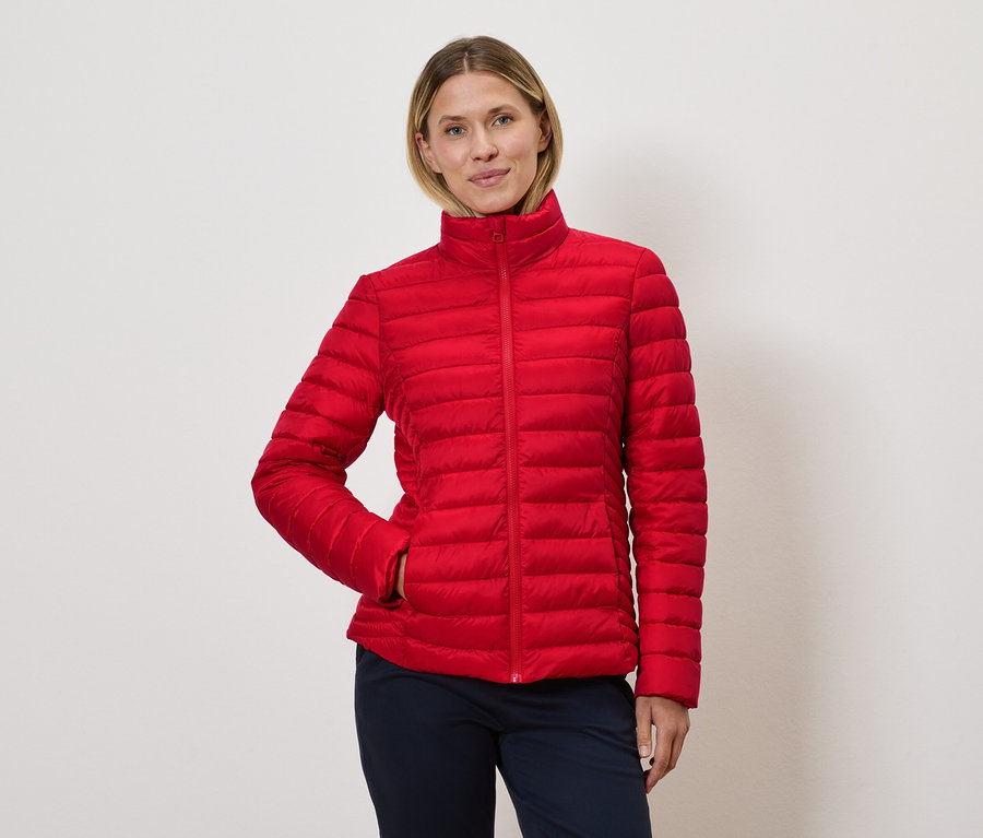 Frau posiert in roter Steppjacke.