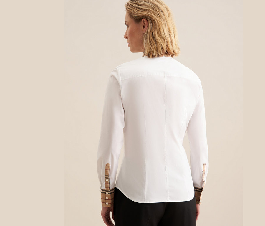 Rückansicht einer Frau, die eine weiße Seidensticker Popeline-Bluse mit Karodetails an den Manschetten trägt.
