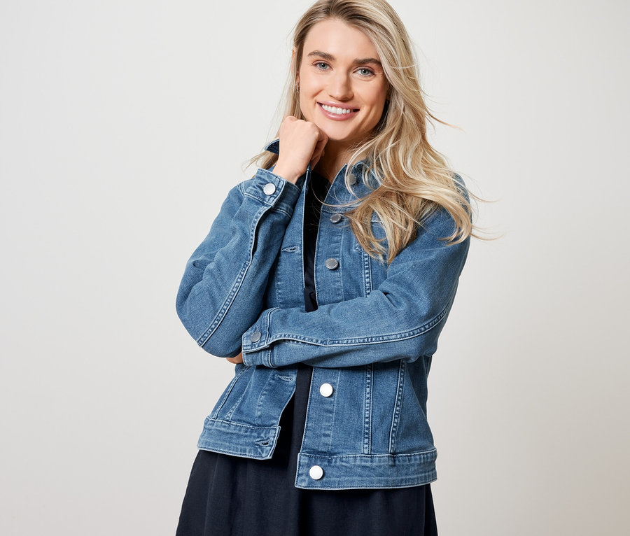 Frau posiert in Jeansjacke und Leinenkleid.