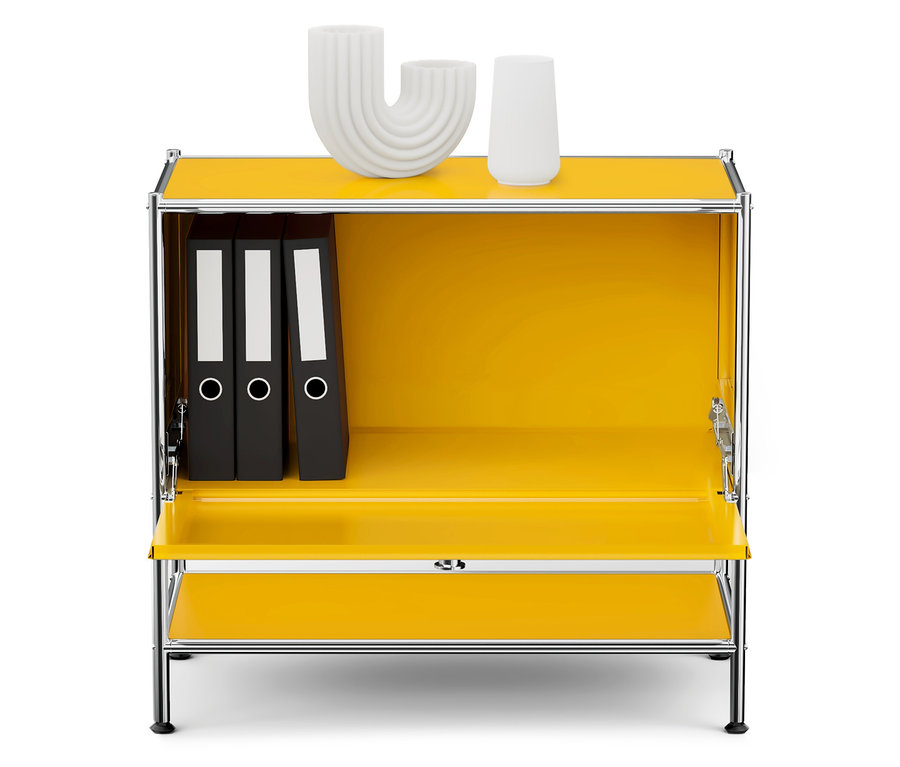 Gelber Schrank mit Chromrahmen, innen drei schwarze Ordner und auf der Oberseite zwei weiße Dekorationen.