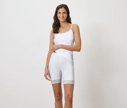 Frau trägt ein weißes Tanktop und kurze Leggings mit Spitzenbesatz.