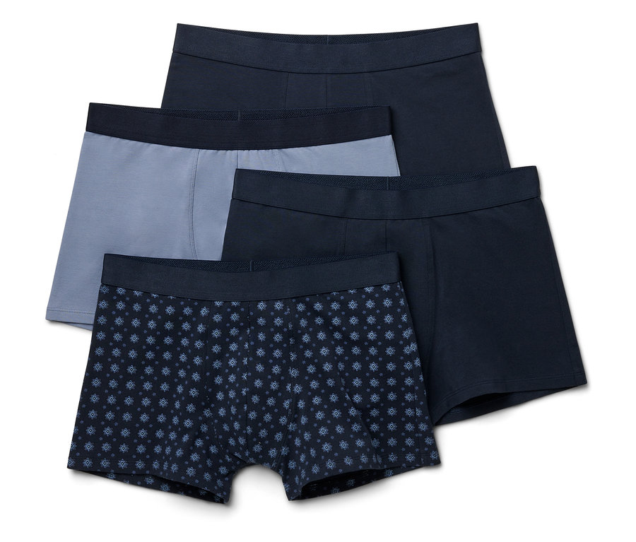 Vier Boxershorts in Marineblau, Grau und mit Muster liegen übereinander.