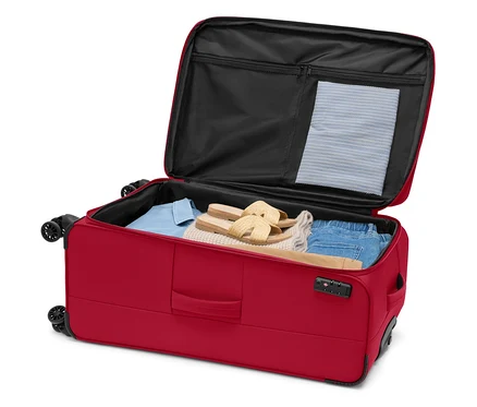 Offener, roter Rollkoffer gefüllt mit Kleidung und Sandalen.