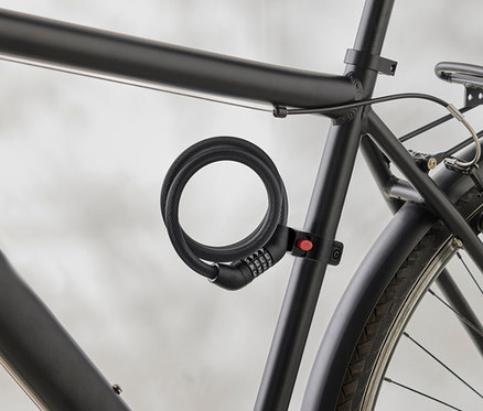 Nahaufnahme eines schwarzen Fahrradrahmens mit einem spiralförmigen Zahlenschloss, das am Rahmen befestigt ist.