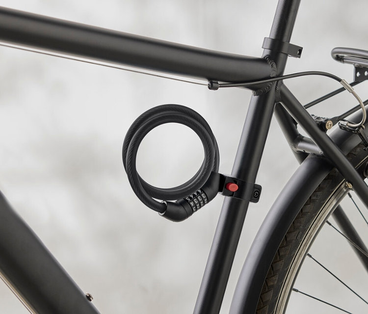 Nahaufnahme eines schwarzen Fahrradrahmens mit einem spiralförmigen Zahlenschloss, das am Rahmen befestigt ist.