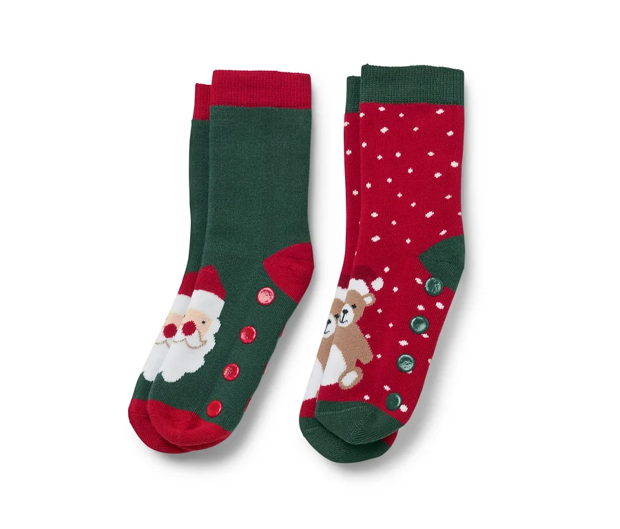 Zwei Paar Weihnachtssocken. Ein Paar ist grün mit roter Spitze und einem Weihnachtsmannbild, das andere ist rot mit weißen Punkten und einem Teddybärbild.