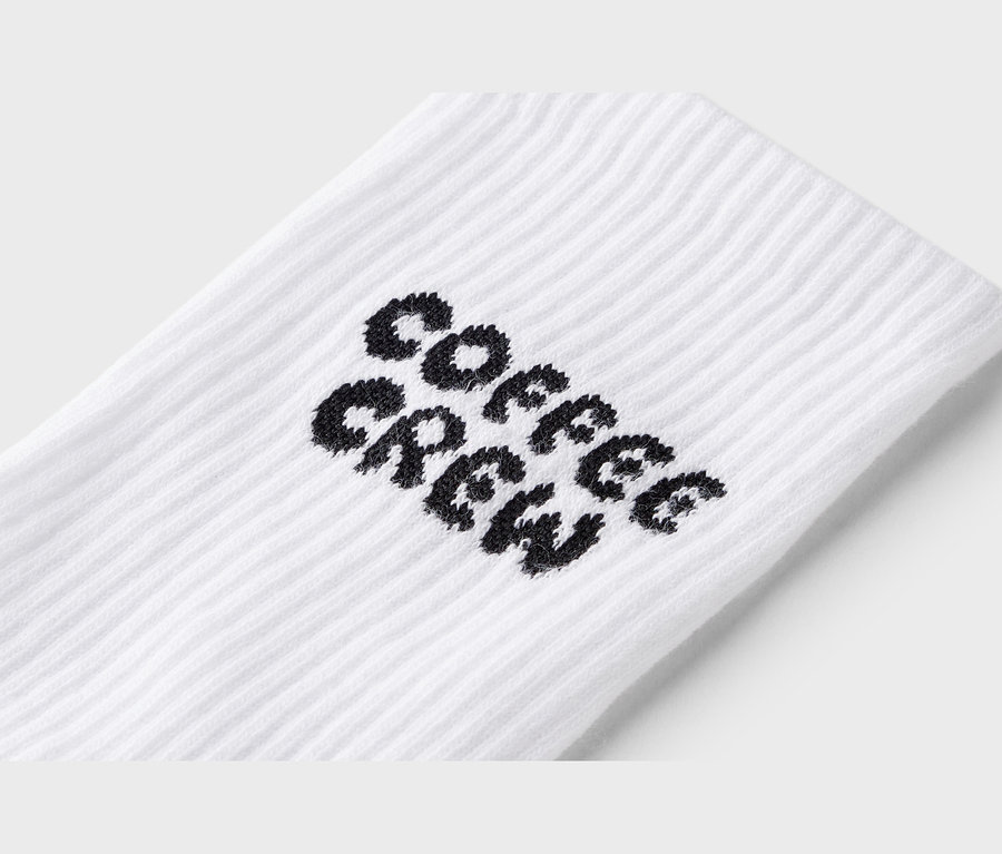 Nahaufnahme einer weißen Socke mit dem schwarzen Schriftzug "Coffee Crew".