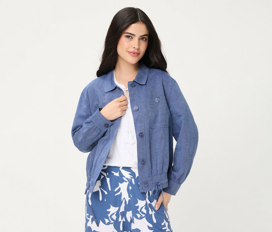 Eine Frau trägt eine blaue Olsen Jeansjacke über einem weißen Oberteil und einem blau-weiß gemusterten Rock.