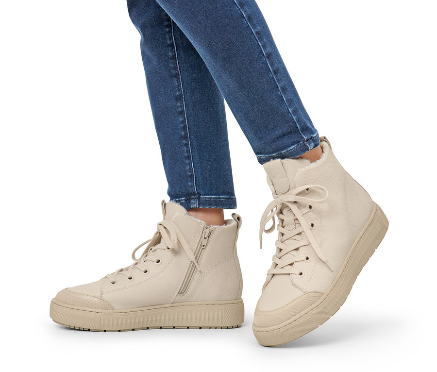 Beine in Jeans tragen beige gefütterte Leder-Sneaker.