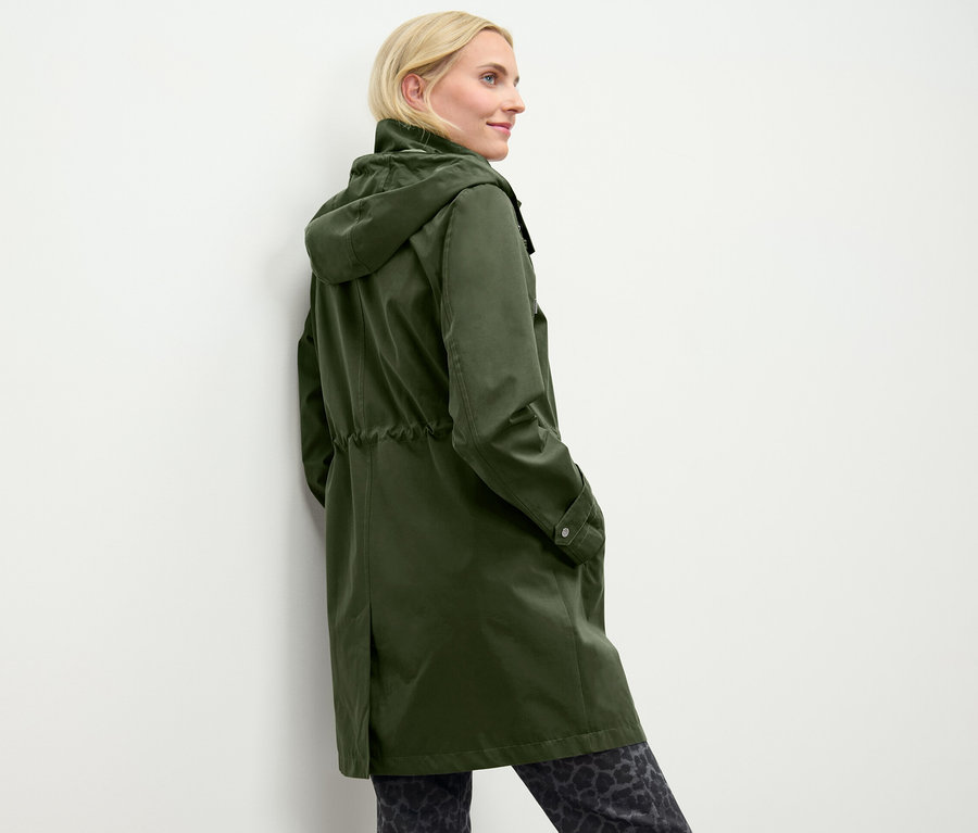 Eine Frau posiert in einem grünen Parka mit Kapuze.
