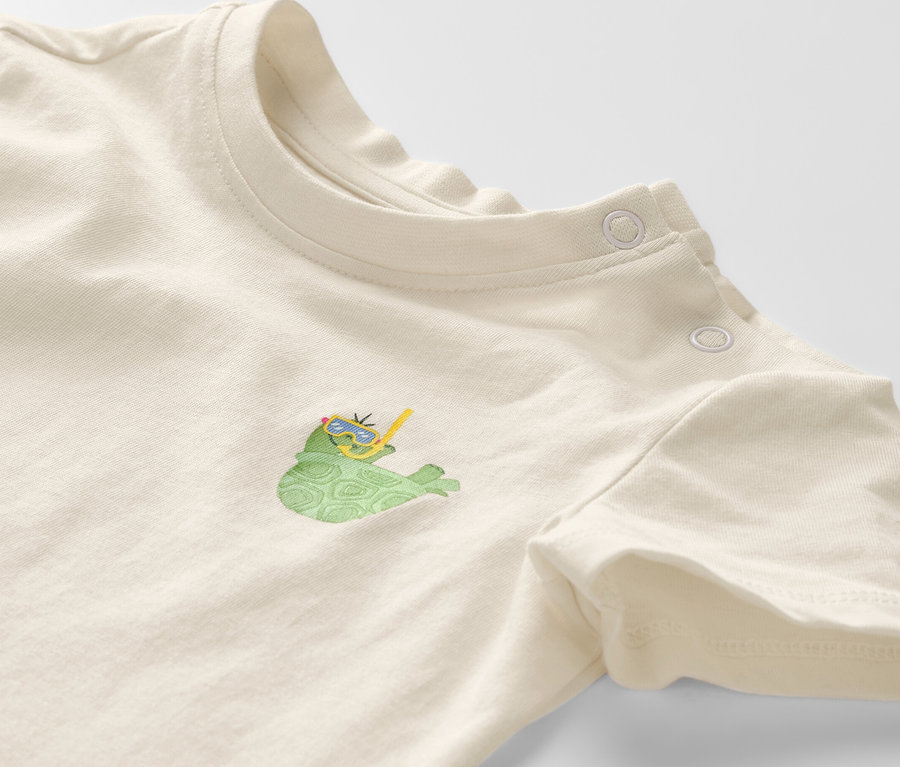Detailansicht eines Kinder-T-Shirts mit kurzen Ärmeln und einem Aufdruck einer Schildkröte mit Brille und Schnorchel.