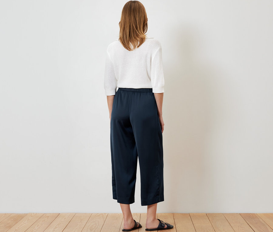 Frau von hinten, trägt eine Satinhose in Navy.