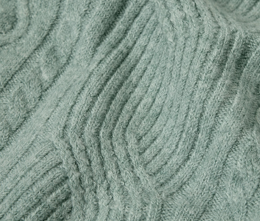 Detailaufnahme der Textur eines Strickpullovers in Salbeigrün.