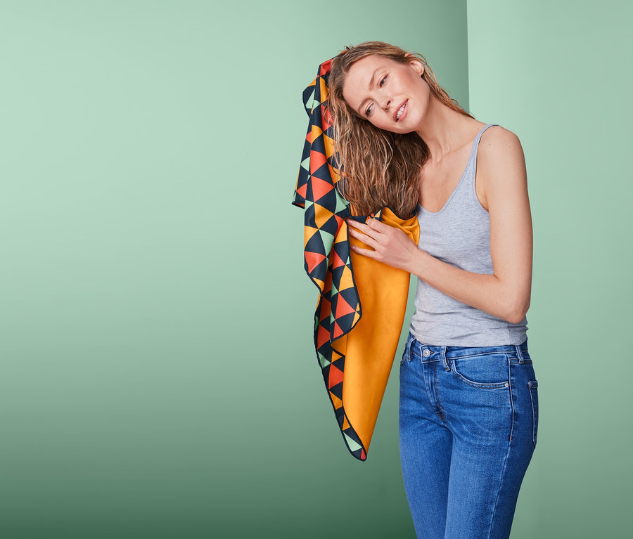 Frau trocknet ihre Haare mit einem mehrfarbigen Outdoor-Handtuch, ca. 50 x 100 cm.