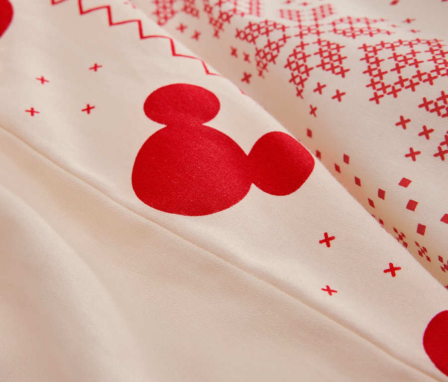Detailansicht einer weißen Bettwäsche mit rotem Mickey Mouse-Muster und Weihnachtsmotiven.