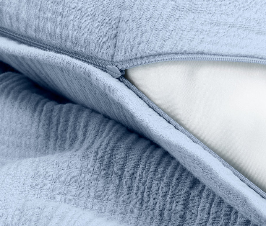 Detailaufnahme eines hellblauen Kissenbezugs mit Reißverschluss, der die weiße Kissenfüllung freilegt.
