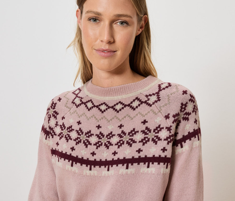 Frau trägt einen rosa Pullover mit Muster.