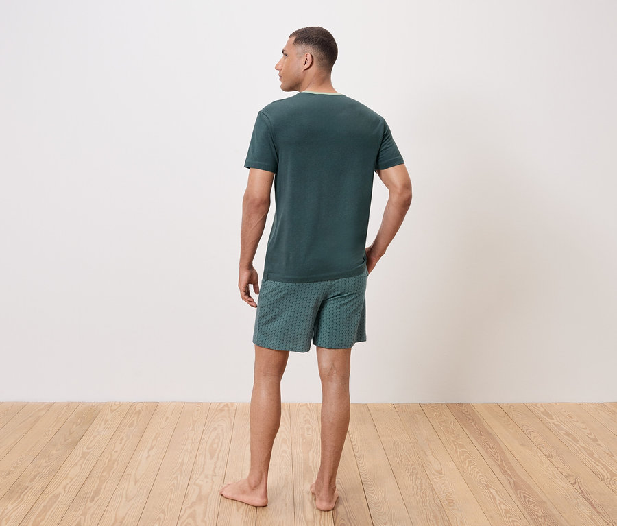 Mann von hinten trägt ein grünes T-Shirt und gemusterte Shorts.