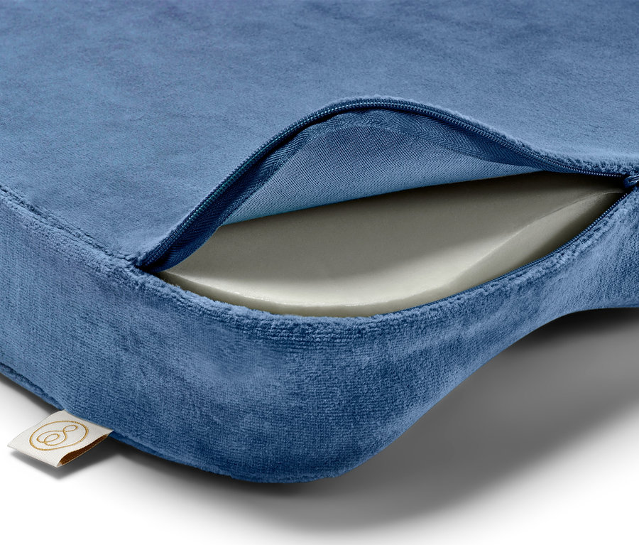Detailansicht eines blauen Kissens mit Reißverschluss, der die weiße Schaumstofffüllung freilegt.