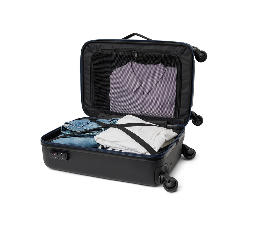 Ein geöffneter, kleiner, schwarzer Hybridkoffer mit Kleidung darin.