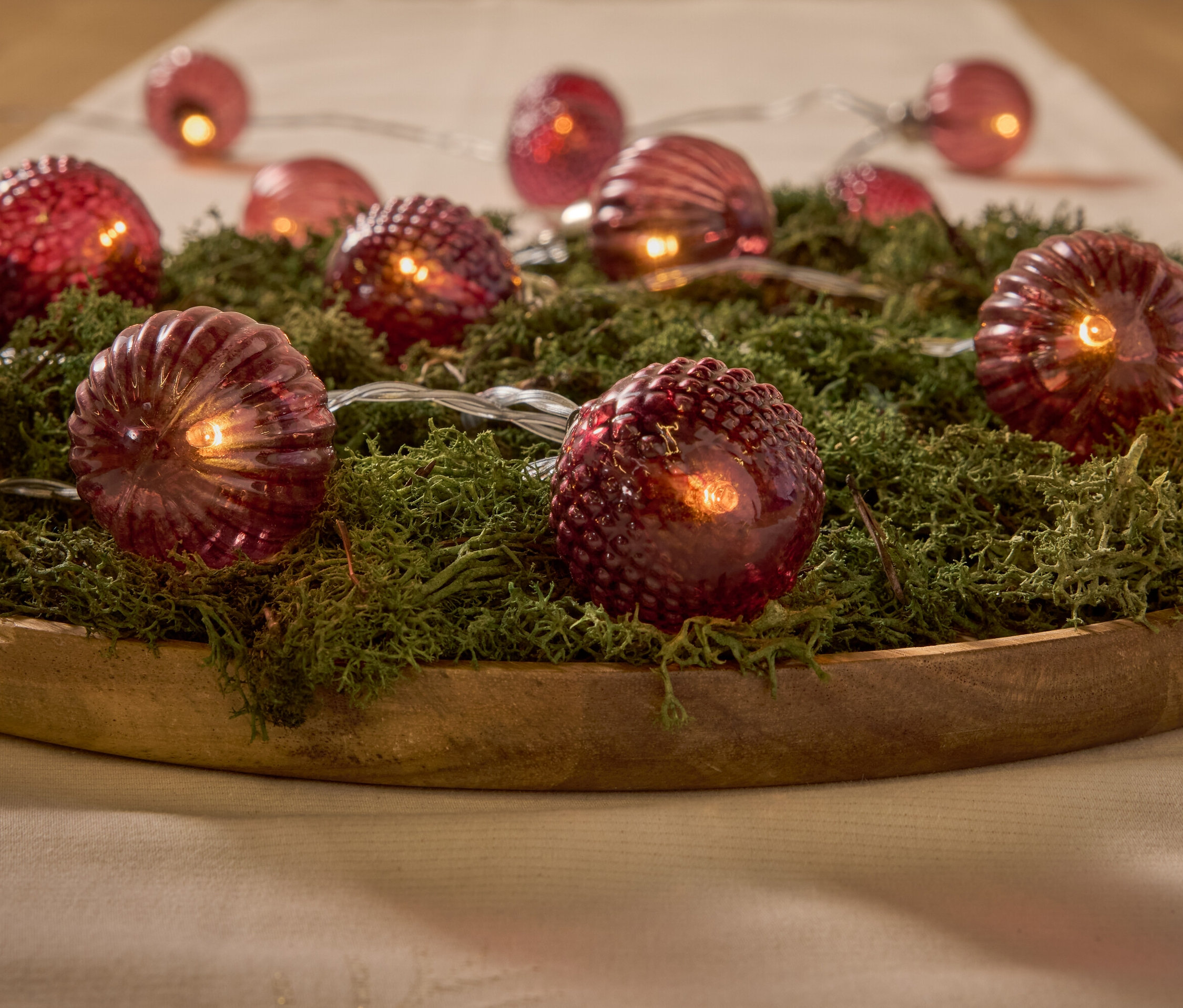 Dekorative rote Lichter auf Moos in einer Holzschale.