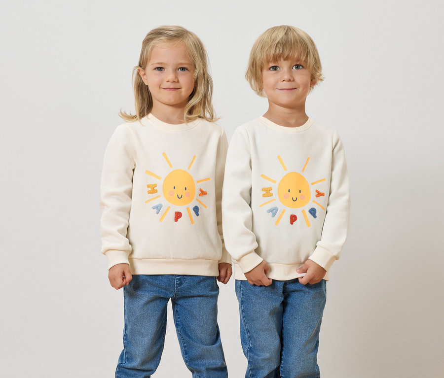 Zwei Kinder stehen nebeneinander und tragen Kinder-Sweatshirts mit angerauter Innenseite und einem Sonne-Motiv.