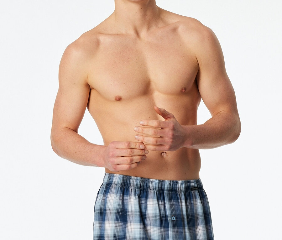 Mann ohne Hemd trägt blaue karierte Boxershorts.