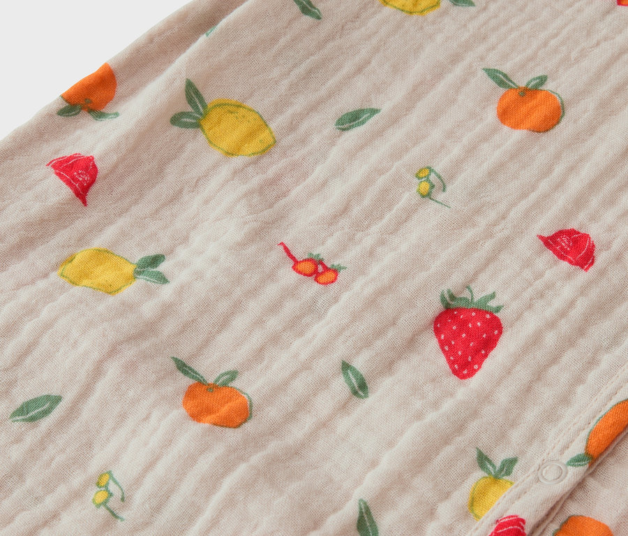 Nahaufnahme eines Stoffes mit Fruchtmuster, darunter Erdbeeren, Zitronen und Orangen.