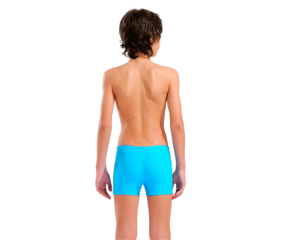 Rückansicht eines Jungen mit braunen Haaren, der türkisfarbene Badehosen trägt.