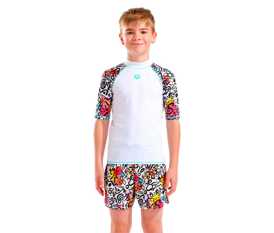 Ein Junge mit blonden Haaren trägt ein weißes Arena-Oberteil mit bunten Ärmeln und passende Shorts.