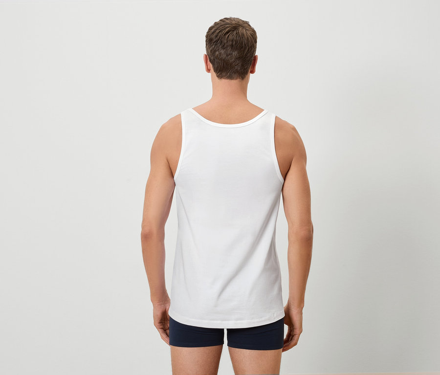 Rückansicht eines Mannes mit weißem Tanktop und blauen Boxershorts vor einem weißen Hintergrund.