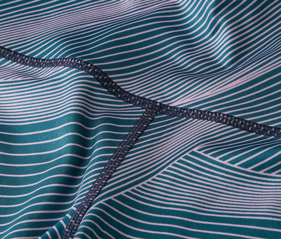 Nahaufnahme von Leggingsstoff mit türkisfarbenen und weißen Streifen und dunklen Nähten.