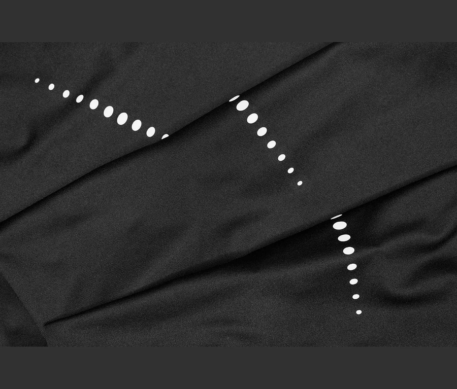 Schwarzer Stoff mit weißen Punkten, die in zwei diagonalen Linien angeordnet sind und Falten sowie Knicke aufweisen.