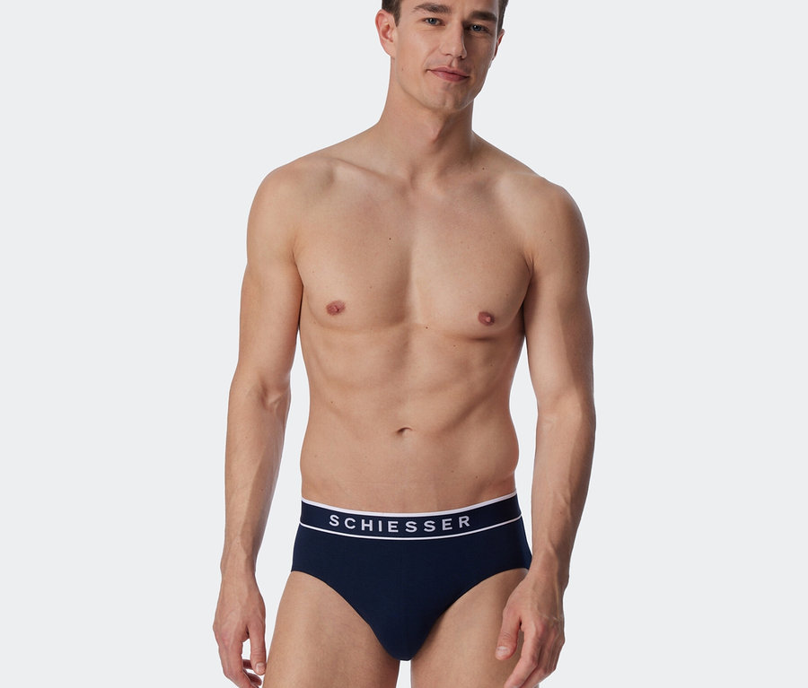 Mann trägt einen dunkelblauen SCHIESSER Rio-Slip mit weißem Logo-Bund.