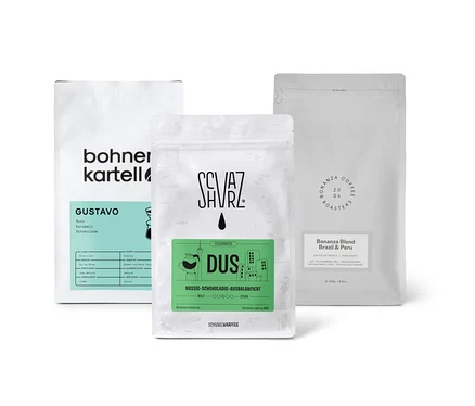 Drei Packungen Filterkaffee Probierset "Dreierpack schokoladig" mit ganzen Bohnen stehen auf einer weißen Oberfläche.