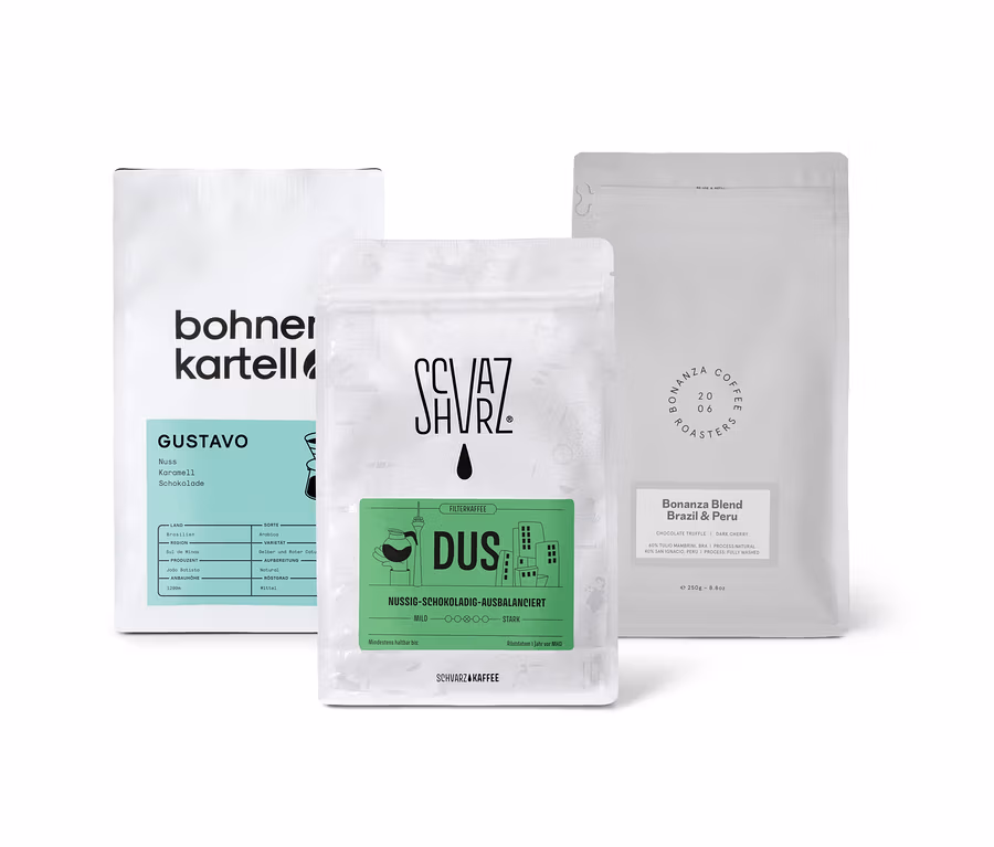 Drei Packungen Filterkaffee Probierset "Dreierpack schokoladig" mit ganzen Bohnen stehen auf einer weißen Oberfläche.