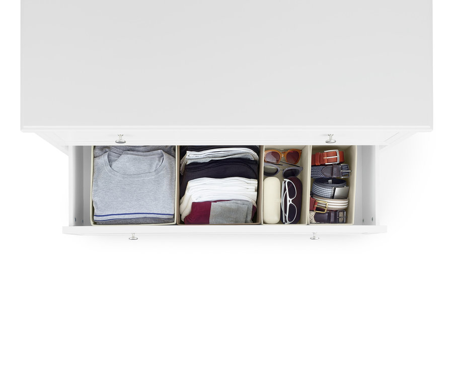Eine geöffnete Schublade einer weißen Kommode enthält zwei große und zwei mittelgroße Schubladen-Ordnungsboxen. In den Boxen befinden sich Kleidungsstücke, Sonnenbrillen und Gürtel.
