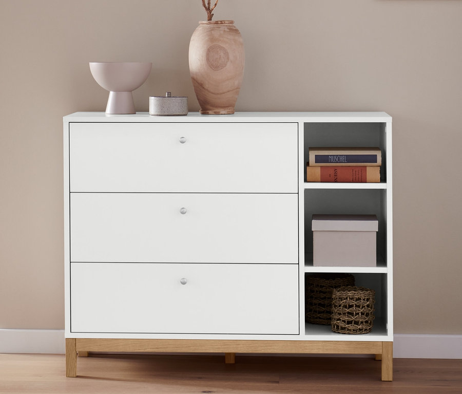 Teilansicht eines Schlafzimmers mit einem hellgrauen Scapa Boxspringbett, ca. 160 x 200 cm, und einer weißen Kommode mit 2 Aufbewahrungskörben.