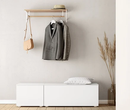 An der Wand hängen eine Wandgarderobe, darunter steht eine Sitzbank, ca. 50 cm, und eine Sitzbank, ca. 100 cm. An der Garderobe hängen ein Sakko und eine Handtasche. Auf der Sitzbank liegt ein Kissen.
