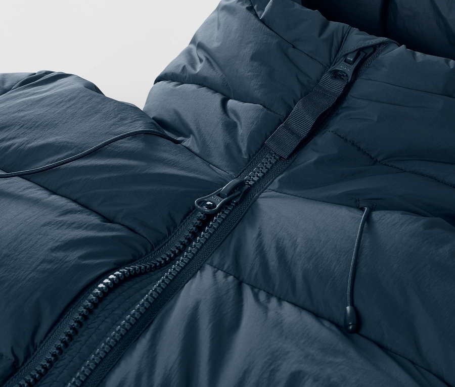 Detailansicht einer dunkelblauen Ski-Steppjacke mit Reißverschluss.