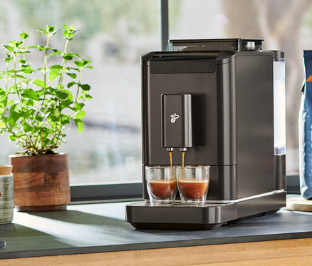 Auf einer Küchentheke steht ein »Esperto2 Caffè« Kaffeevollautomat in Granite Black, der Espresso in zwei Gläser zubereitet.