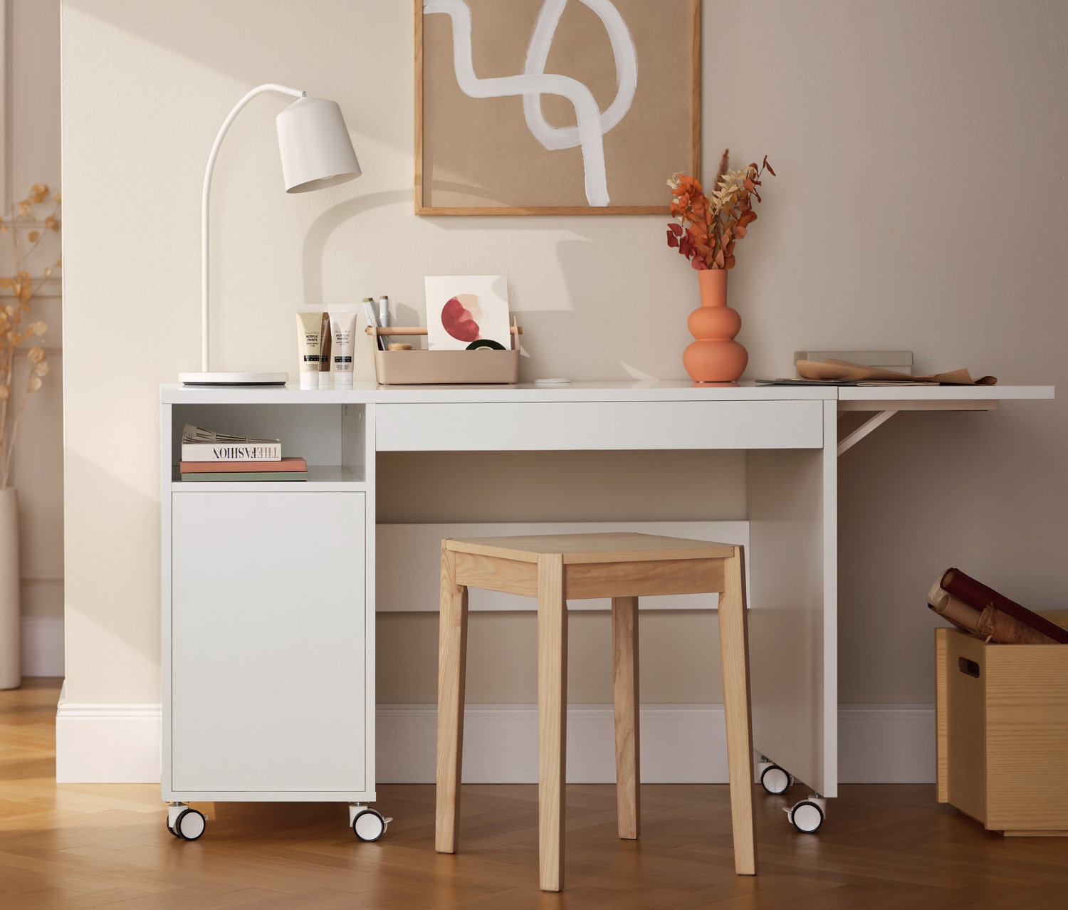 Innenraum mit einem dekorativen Regal aus Eschenholz, einem Multifunktionstisch mit erweiterbarer Tischplatte, einer LED-Akku-Tischleuchte und einem Hocker aus Eschenholz.