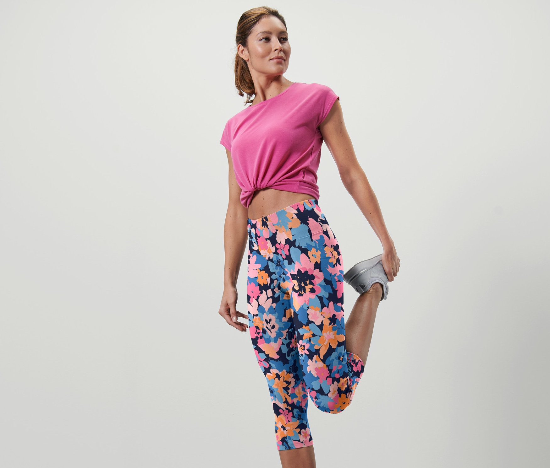 Frau dehnt Bein in 3/4-Sporttight mit Blumenmuster.