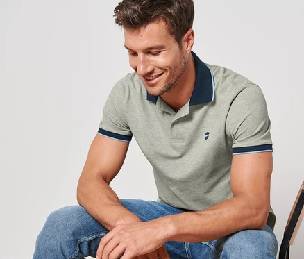 Mann sitzt auf einem Stuhl und trägt ein grau meliertes Piqué-Poloshirt.