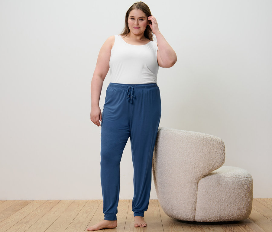 Frau steht und trägt 2 Hemdchen in Dunkelblau/Weiß und eine Pyjamahose.