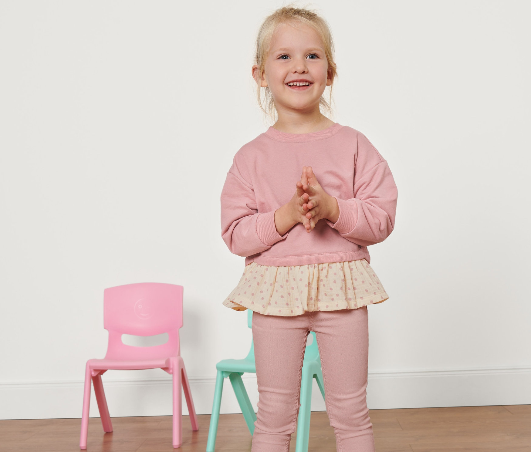 Lächelndes blondes Mädchen im Kinder-Sweatshirt posiert im Studio.