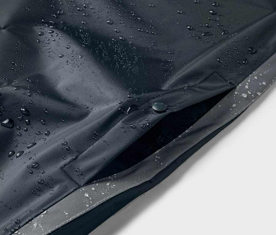 Detailansicht eines blauen Kinder-Regenponchos mit Wassertropfen und Tasche.